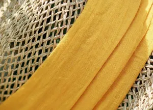 Detailed close-up view of hollow woven straw hat texture paired with soft yellow fabric ribbon.
