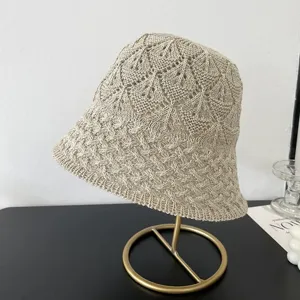Detailed view of the beige knit bucket hat, showcasing the hollow mesh diamond pattern.