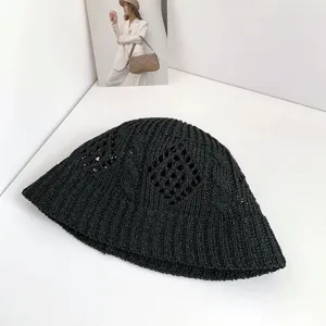 Close-up detail of black hollow knit bucket hat with diamond cable pattern texture.