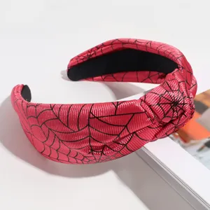 Red knotted headband featuring a black spider web pattern, perfect for Halloween styling.