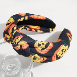 Close-up detail of a dark Halloween pumpkin printed knotted headband, black and orange.