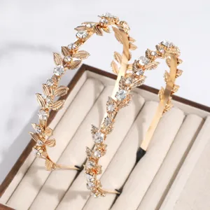 Detalle de diadema dorada con hojas y estrás, accesorio para el pelo de cristal brillante.