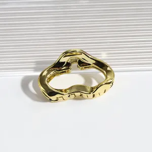 Goldfarbene Metall Haarklammer Detailansicht, unregelmässiges geometrisches Design, glänzend.
