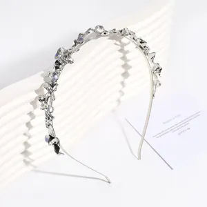 Diadema de metal plateado con diseño fluido irregular y pedrería iridiscente detalle.
