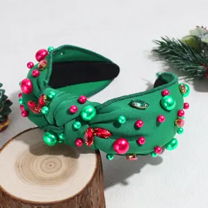 Detailed view of green knotted headband decorated with red and green pearls and rhinestones.