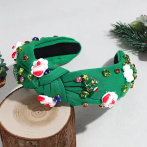 Close-up detail shot of green knotted Christmas headband featuring rhinestones and holiday charms.