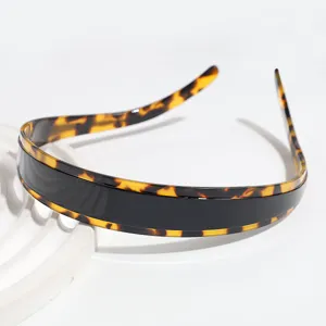 Detailed view of the chic tortoiseshell and black spliced headband showing smooth glossy finish.
