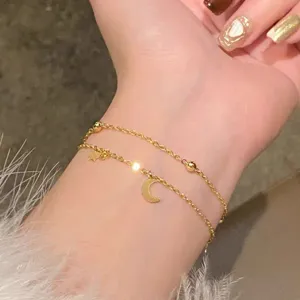 Double layer gold color chain bracelet featuring delicate moon and star charms and beads.
