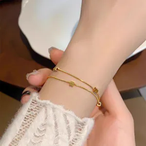 Close-up detail of delicate double-layer gold chain bracelet with cute mini cube beads.