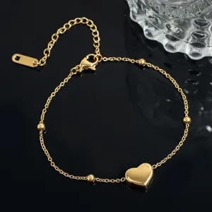 Close-up detail view of the gold-plated heart pendant and delicate chain bead bracelet.
