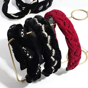 Detailed view of fashionable velvet braided headbands with rhinestones on display stand.
