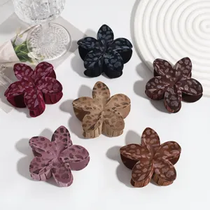 Vue détaillée de pinces à cheveux fleuries en léopard floqué à la mode dans des tons bruns et noirs.