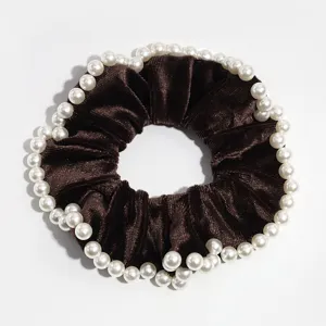 Elastico per capelli in velluto marrone con bordo di perle finte, vista in primo piano.