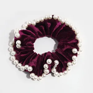 Vista dettagliata di un elegante elastico per capelli in velluto viola scuro con perle.