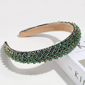 Détail rapproché du serre-tête luxueux en strass verts avec un design rembourré.