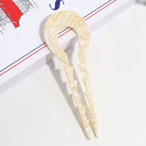 Detaillierte Nahaufnahme einer weissen Acetat U-foermigen Haargabel mit kleinen Zaehnen.