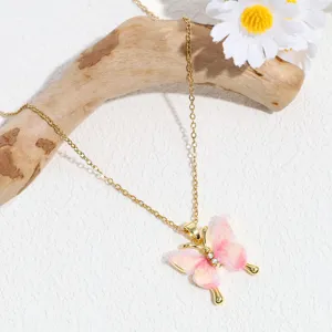 Close-up detail view of the elegant pink butterfly pendant necklace displayed on driftwood.