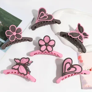 Dettaglio di mollette per capelli opache rosa e marrone, con simpatici fiori e farfalle per donna.