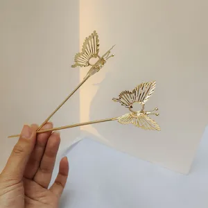 Gold metal butterfly hairpin detail shot, elegant hollow hair fork for chic updos and styling.