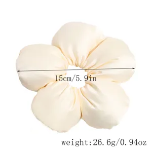 Detailed close-up view of the beige satin sponge flower hair scrunchie, highlighting its size.