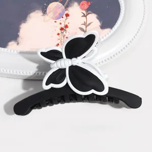 Vista dettagliata dell'elegante molletta per capelli a farfalla opaca nera e bianca.