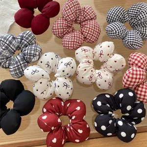 Detailed view of assorted fabric flower hair scrunchies featuring plaid, polka dot and bow designs.