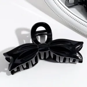 Pinza de pelo negra con lazo para mujer, accesorio elegante y brillante minimalista detalle.
