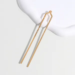 Gold U-shaped hair fork detail view, elegant metal hairpin close-up showcasing texture.