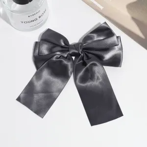 Close-up detail of the elegant dark grey satin bow hair clip, showcasing smooth fabric.