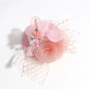 Close-up of pink mesh feather fascinator hair clip detail, elegant party headwear texture view.