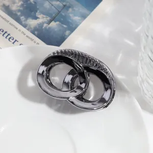 Detailopname van donkerzilveren geometrische haarclip met in elkaar grijpende ringen textuur.