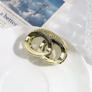 Detailopname van een gouden geometrische metalen haarklem met elegant ovaal design.
