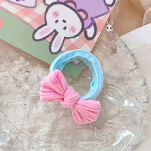 Gros plan d'élastique à cheveux nœud rose, bande bleue extensible, bel accessoire de coiffure.