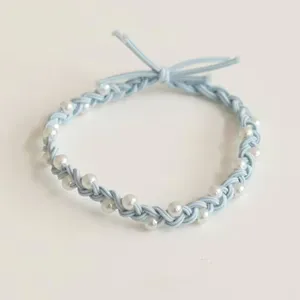 Close-up of blue braided hair rope with white faux pearls, showing fine texture and elasticity.