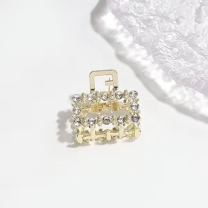Detail shot of a gold-tone mini hair claw clip decorated with sparkling rhinestones.