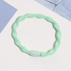 Light green woven hair tie with decorative bead, simple elastic hair band detail shot.