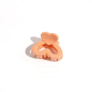 Close-up detail of a sweet peach heart hair claw clip, cute mini hair accessory for styling.