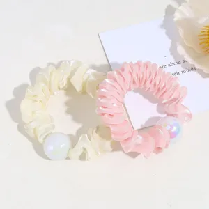 Vue détaillée de chouchous plissés mignons avec perle brillante en rose et crème.