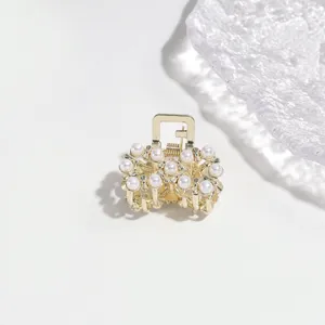 Exquisite detail of gold alloy small hair claw clip decorated with elegant white faux pearls.