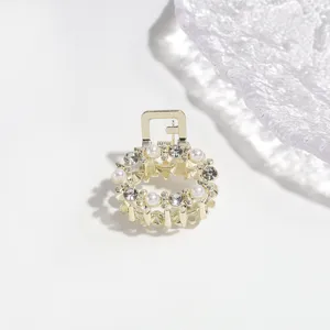 Elegant mini gold hair claw clip featuring faux pearls and rhinestones for styling hair.