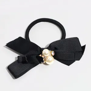 Detailed shot of black ribbon hair tie with faux pearls and rhinestones, elegant design.