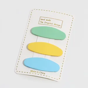 Candy color oval hair clips detail view, featuring matte green, yellow and blue hairpins.