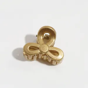 Gold metal mini hair claw clip detail, matte finish clover design for fine hair styling.