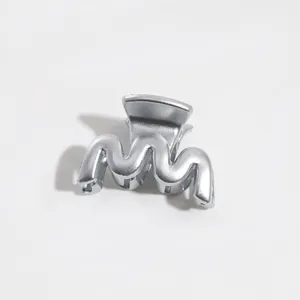 Close-up detail of a stylish silver wavy hair claw clip, compact design for daily styling.