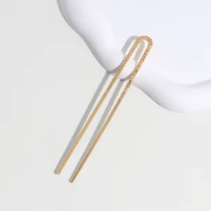 Close-up detail of a minimalist gold U-shaped hair fork with delicate engraved pattern.