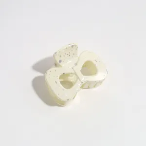 Close-up detail of a cream bow hair claw clip with silver speckles for styling.