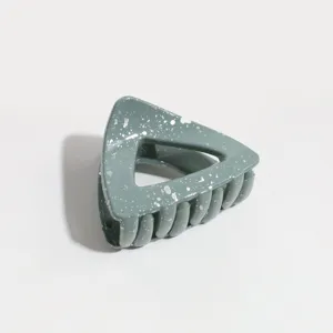Close-up detail shot of a stylish green triangle hair claw clip featuring silver speckles.
