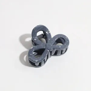 Close-up detail of a dark greyish-blue bow hair claw clip with white paint speckles texture.