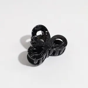 Detailed shot of the black bow hair claw with white speckles, ideal for half-up hairstyles.