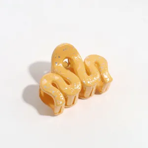Detail shot of a yellow wavy hair claw clip with silver speckles, secure daily hair styling accessory.